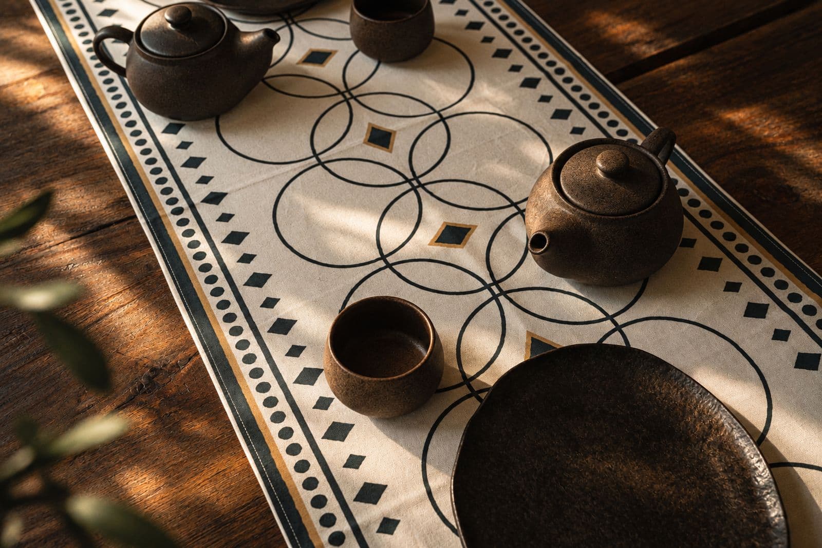 Cream KIND table runner with interlocking circles and diamonds, set with stoneware teapots and cups